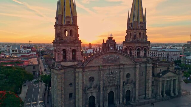 Cinematic drone shot flying between the iconic towers of Guadalajara Cathedral at sunset revealing Teatro Degollado in the background in historic downtown Guadalajara Mexico.