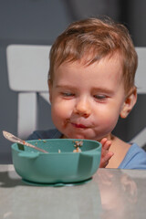Child enjoying calm breakfast moment with bowl of oatmeal and spoon.