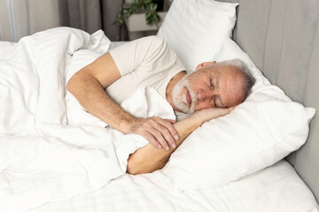 Cozy morning in hotel bed with elderly man enjoying peaceful sleep and relaxation