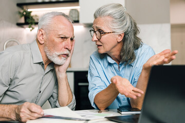 Couple discussing household finances while using laptop at home
