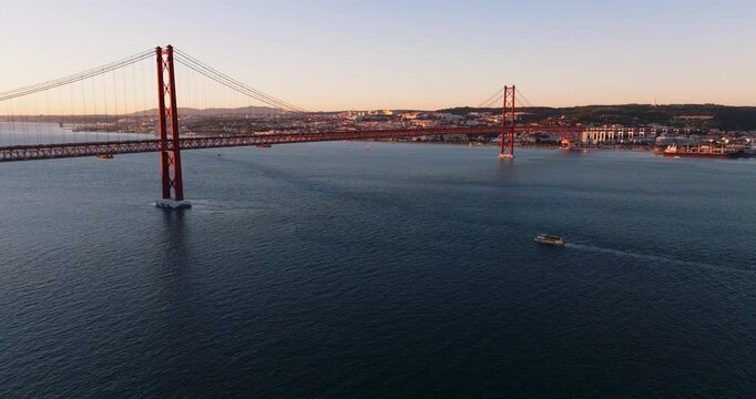 Wide drone view of 25 de Abril Bridge and Tagus River framed by Lisbon shoreline