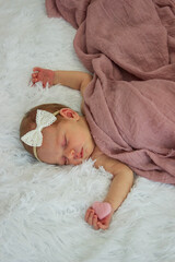 Sleeping newborn baby on white fur with pink heart.