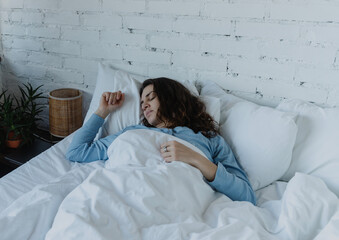 Young serene woman sleeping peacefully in cozy bed with white linens at home.Young serene woman sleeping peacefully in cozy bed with white linens at home