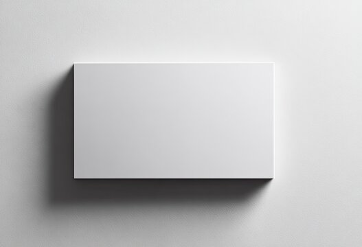 A rectangular, blank white surface casts a shadow on a white background, top-down view