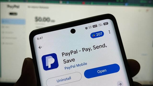 Hand holding smartphone with PayPal app open on screen