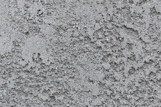 Gritty wall texture with embedded aggregates, suitable for construction materials, raw surfaces, and industrial backgrounds.