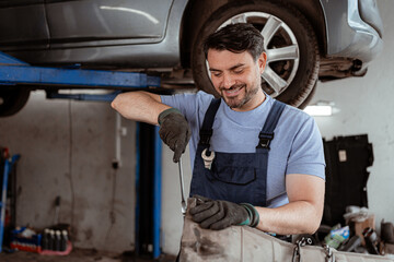 Mechanic works on car repair under vehicle lift in auto shop during daytime
