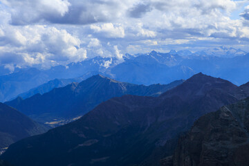 Obraz premium Panorama view of Aosta Valley mountains with summit Gran Paradiso in the background seen from alpine hut Rifugio Guide della Valle d'Ayas in summer in Pennine Alps, Italy