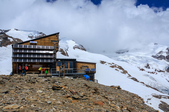 Mountaineers, alpine hut Rifugio Refuge Quintino Sella au Felik and mountain glacier panorama in summer in Pennine Alps, Italy