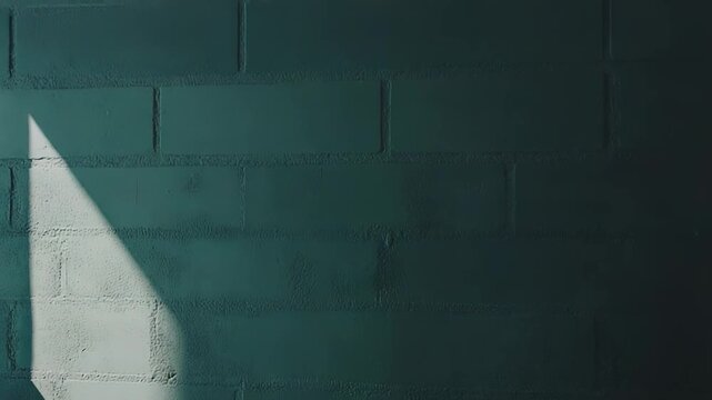 Concrete block wall showing a textured surface where a strong diagonal shadow creates an abstract geometric pattern with contrasting light and dark teal shades
