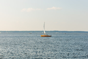 Obraz premium A sailboat is floating in the ocean with a few other boats in the background