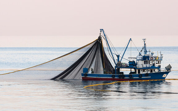 The fishing boat is casting its nets into the sea hoping for a good catch.