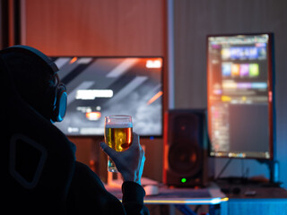 Fototapeta premium man wearing headphones and having a beer glass in front of a computer. Relax and play computer games. Drinking beer on the computer