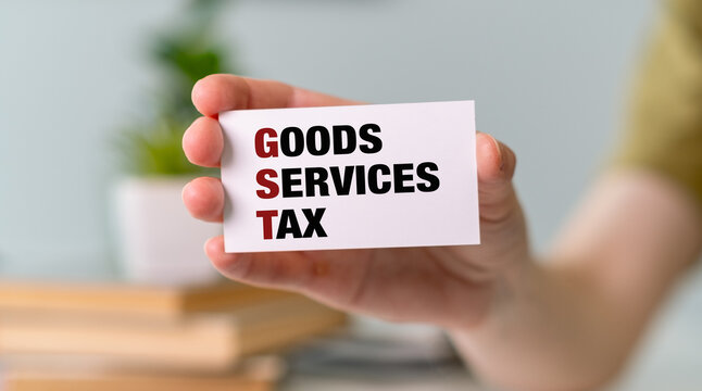 Paper with GST Good Service Tax in hand on charts, business concept