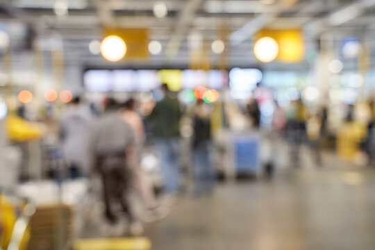 Blurred crowd in busy shopping mall with diverse adults and teens engaged in shopping activities.