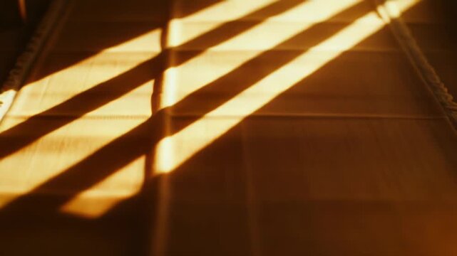 Warm sunlight through a window casts bold striped shadows across a textured rug, bathing the floor in golden hour glow and creating a cozy, serene indoor pattern