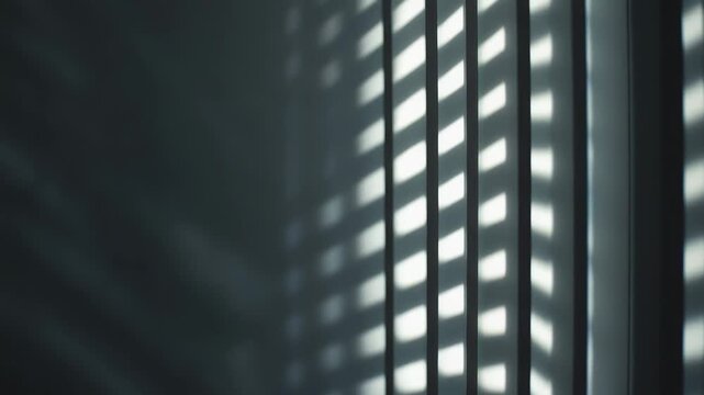 Vertical blinds casting rhythmic light and shadow patterns on a dim wall, creating a dynamic abstract composition with strong contrast and minimalist appeal