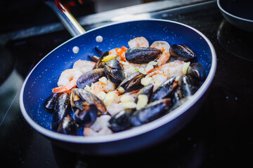 Apetyczne małże i krewetki smażone na patelni © Artur