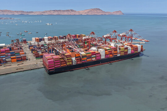 Aerial view of a seaport with a huge container ship in the process of unloading for massive intercontinental trade
