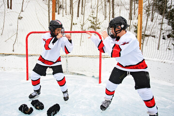 Obraz premium Ice hockey fight. Two teens play hockey outside in uniform. Sports winter games outdoors in winter.