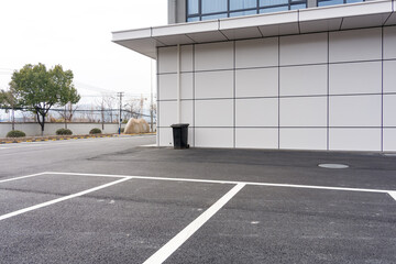 Obraz premium Empty parking lot beside modern building with asphalt surface and greenery strip