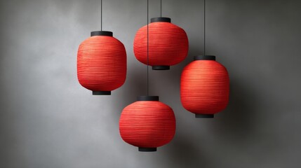 Obraz premium Four red lanterns hanging from the ceiling. The lanterns are red and have a paper-like texture. The lanterns are hanging from a gray background