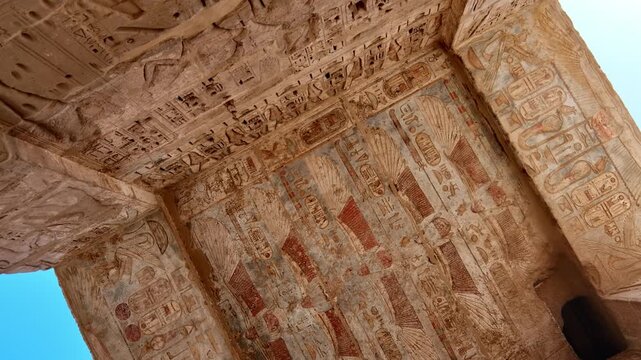 Medinet Habu temple painted ceiling with vulture goddess and hieroglyphs in red orange colors in Luxor Egypt, ancient Egyptian astronomical decorations and cartouches;.