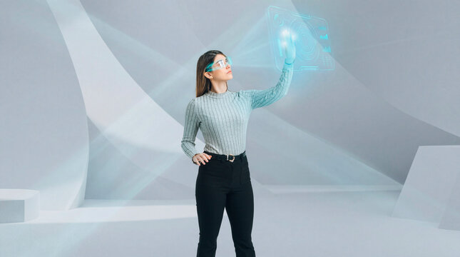 Woman using augmented reality glasses to control holographic interface in futuristic studio