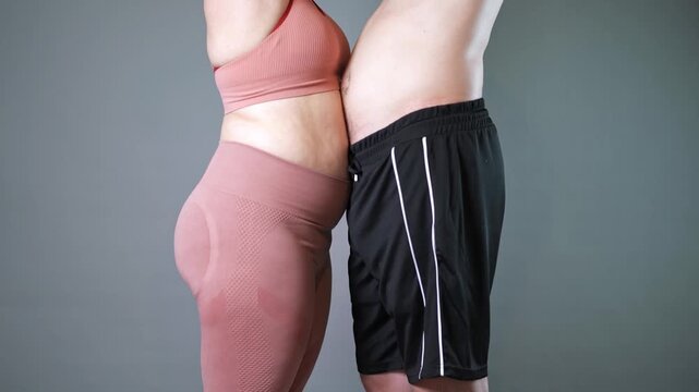 Fat couple doing vacuum exercise, man and woman inhale and exhale their stomachs during a breathing exercise, bellies in yin yang shape, breathwork and fitness, gray background