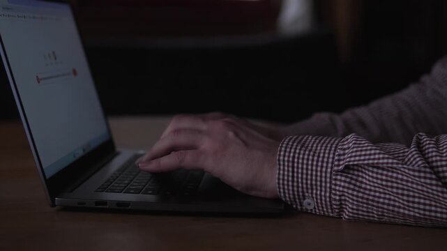 Man Editing Document. Man Refining Text On Laptop Under Dim Lighting. Caucasian Male Engaged In Careful Proofreading And Revision On Portable Device In Subdued Illumination