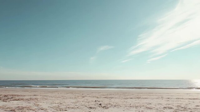 Sandy beach dunes with dry grass separating the tranquil land from the calm sea under a beautiful expansive sky, reflecting serenity and natural beauty