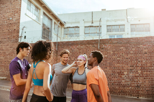 Young adults huddle for outdoor workout by brick wall