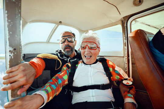 Senior woman tandem skydiving with instructor inside plane