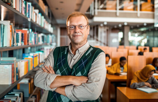 Confident professor posing in university library reading room
