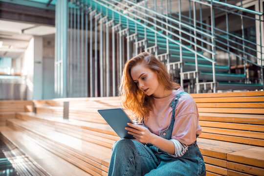 Young woman studying on tablet in modern university atrium