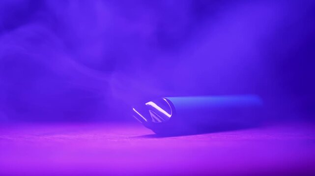 A disposable electronic cigarette lies on a table surrounded by swirling vapor with shifting neon lights. Concept of nicotine addiction, smoking alternatives, and trendy nightlife culture.