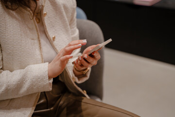 A business woman is corresponding or scrolling through the Internet feed. Women's hands with a close-up of a smartphone.