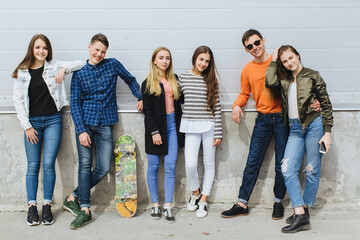 Obraz premium Group of diverse teenagers posing together, showcasing friendship, youth, and urban lifestyle against a textured wall