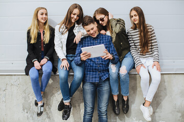Fototapeta premium Group of teenagers connecting with digital tablet, sharing online content, having fun together, and socializing
