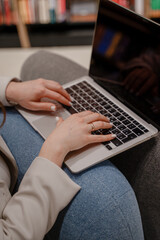 Close-up of a laptop and a woman's hands. The girl is working on a laptop. Vertical photo. Remote work.