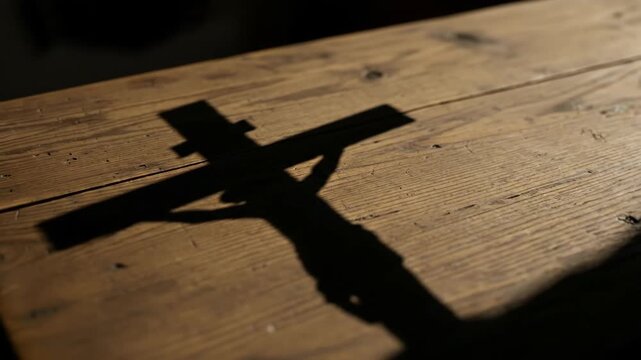 Shadow of a crucifix on a wooden church pew, warm sepia tones, representing Ash Wednesday and Lenten penance