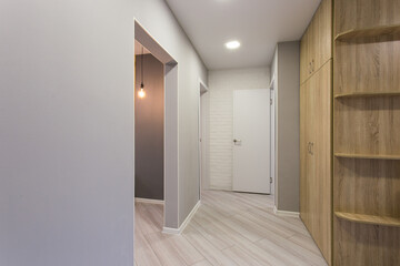 Fototapeta premium A modern hallway with wooden cabinets and a visible door.