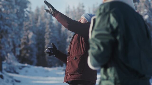 Man in winter throws snow, Person clad in red jacket accidentally falls into snow among trees during cold season