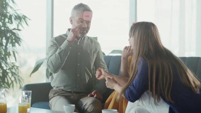 Lively family moment with silent guessing game, Father and daughters engage in playful silent guessing activity