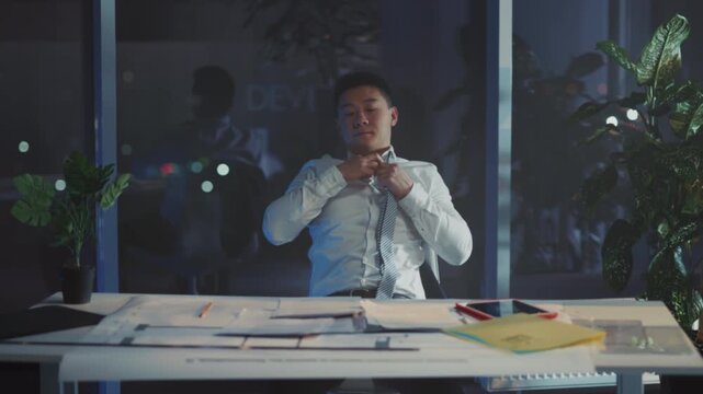 Evening office work scene, Asian entrepreneur focused on planning late into night with city skyline backdrop