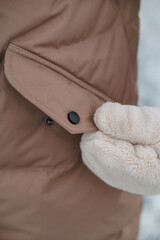 Close-up of a brown puffer vest pocket with a white fluffy glove © Northern life
