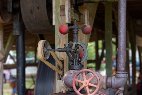 History. Old Centrifugal flyball governor on a vintage steam-powered sawmill, regulating engine speed through rotating iron balls and belt drive