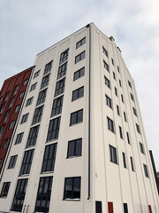 Modern high rise residential building with white facade and dark windows architecture, new apartments for real estate development