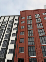 Fototapeta premium Modern apartment building with white and red brick facade. Residential skyscraper architecture for real estate and urban development. Urban design concept.