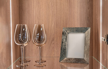Wine glasses and photo frame on illuminated glass shelf